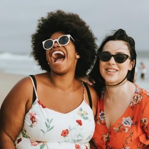 Two women laughing at the beach.