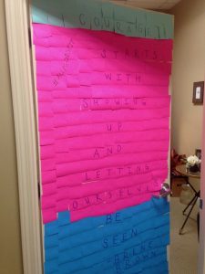 Amy's office door covered in sticky notes that says "Courage starts with showing up and letting ourselves be seen" by Brene Brown
