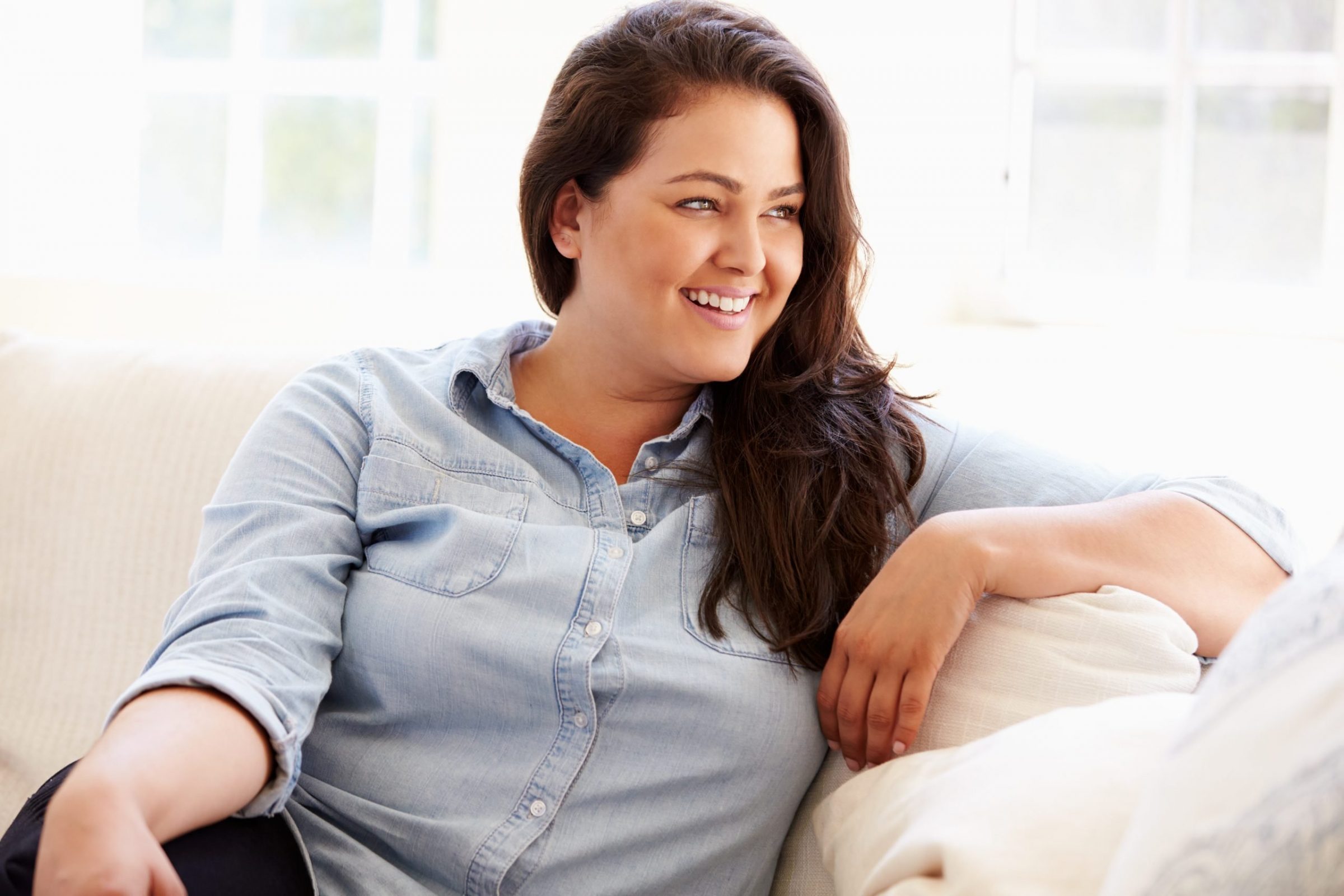 Woman smiling while on a couch with her arm over it