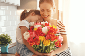 Woman holding her daughter and flowers