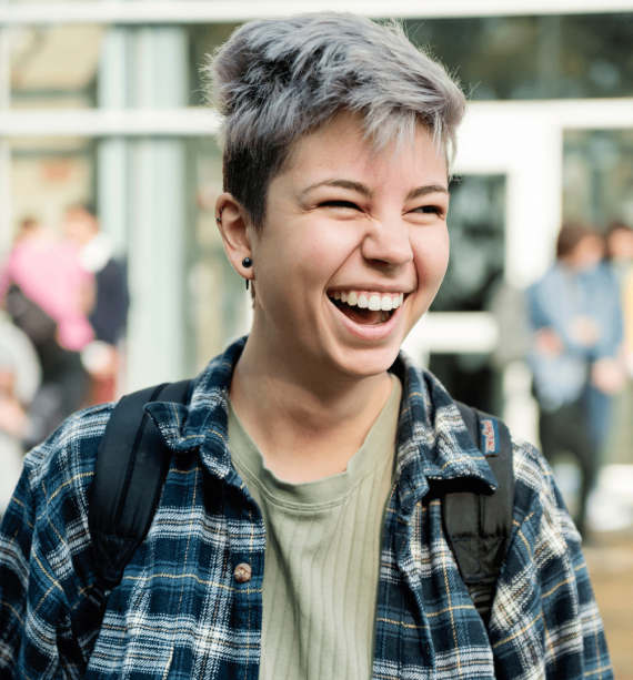 non binary individual smiling ad laughing outside