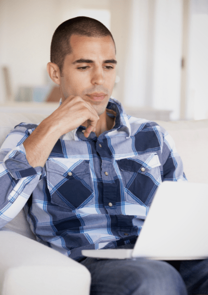 young man wearing flannel is engaged with virtual program on his laptop