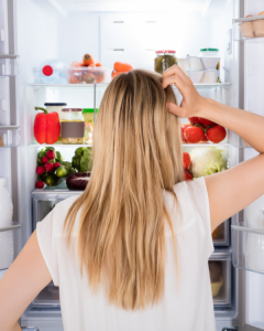 young blonde-haired woman looks in the fridge