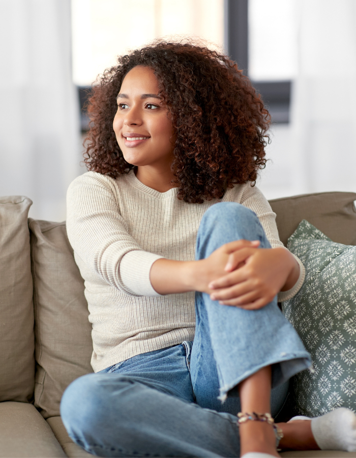 young woman with curly hair sitting on the couch