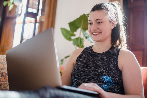 A young woman with a ponytail engages happily with other virtual program clients.