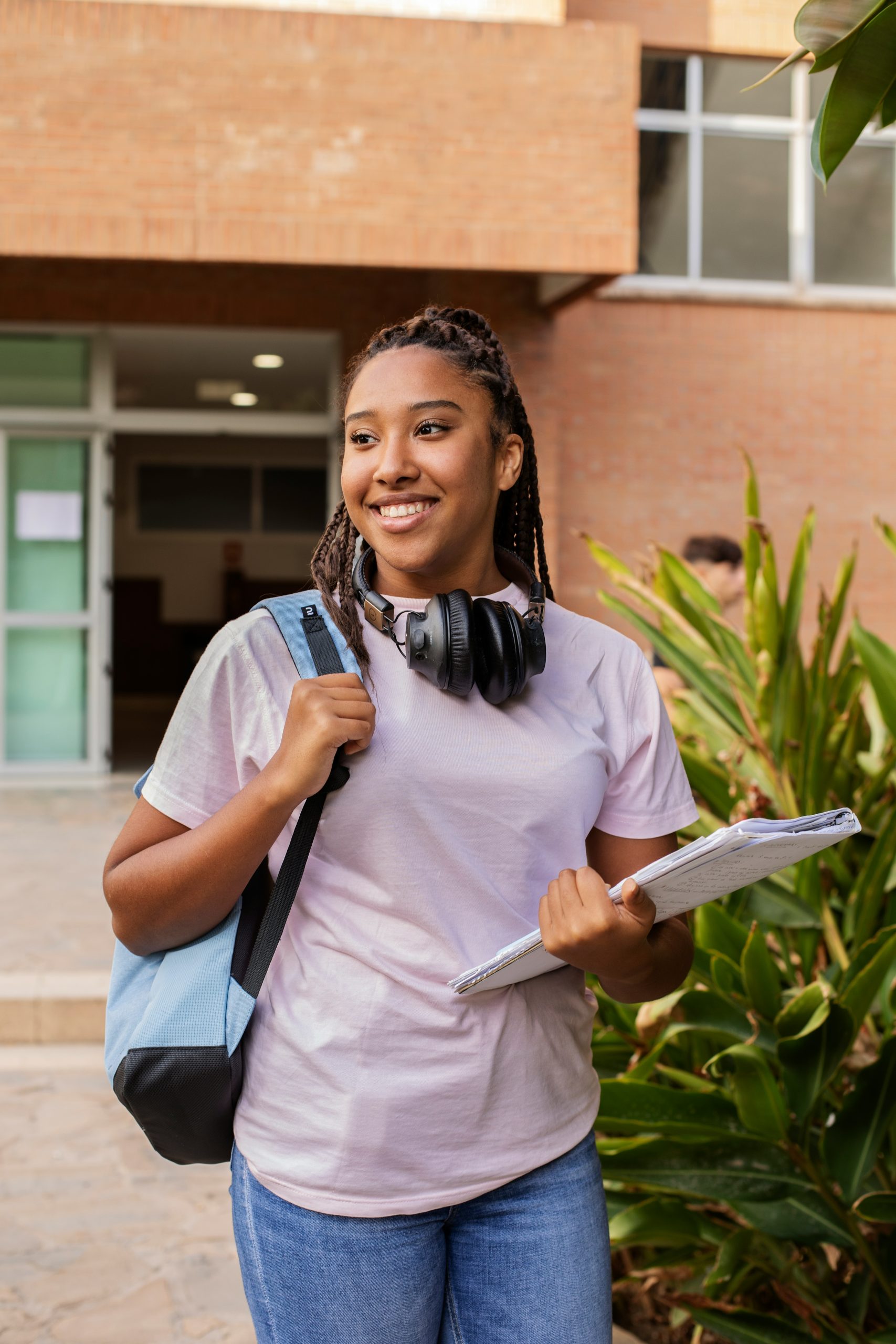young girl with headphones, a notebook, and a backpack